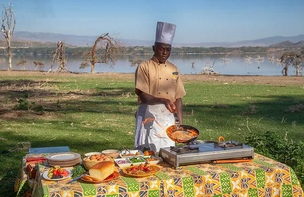 Grand Burnham Hut chef preparing breakfast outdoors beside a lake